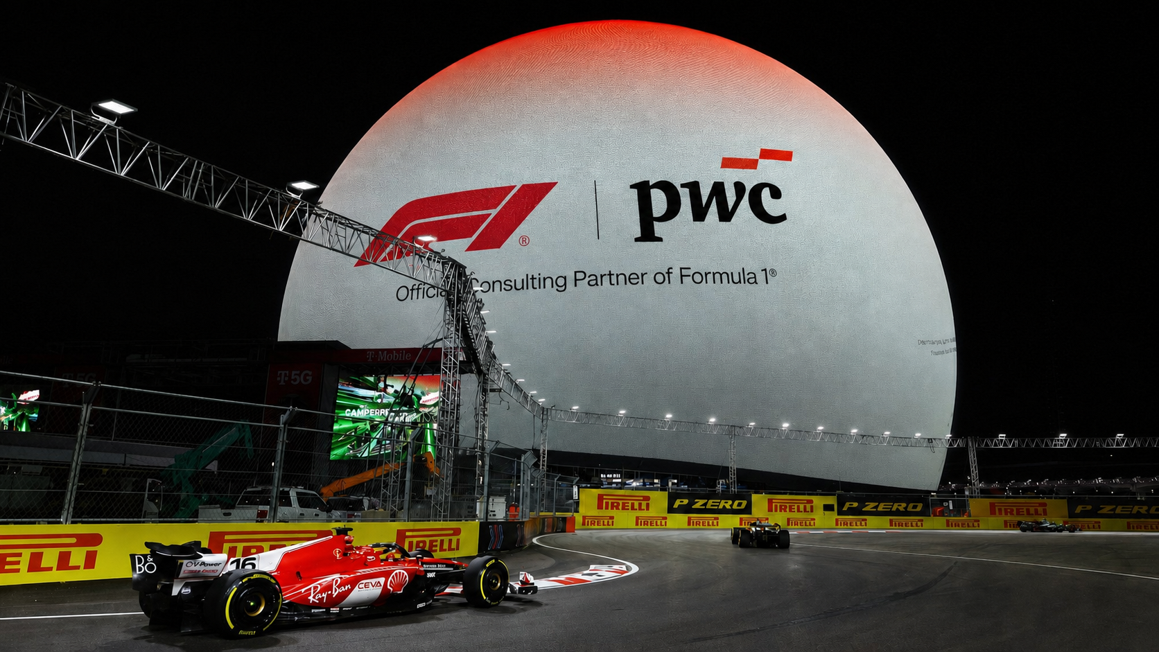 Ferrari F1 car on the Las Vegas street circuit in front of Sphere displaying the F1 and PwC partnership